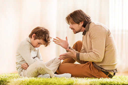 Mid adult father talking to his little boy and scolding him.  