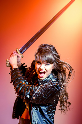 Beautiful girl in dressed as warrior brandishing her sword and shouting loudly
