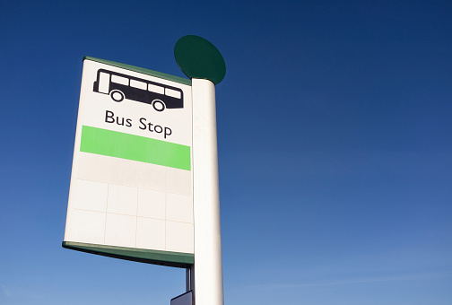 A simple sign for a bus stop, against a clear blue sky.