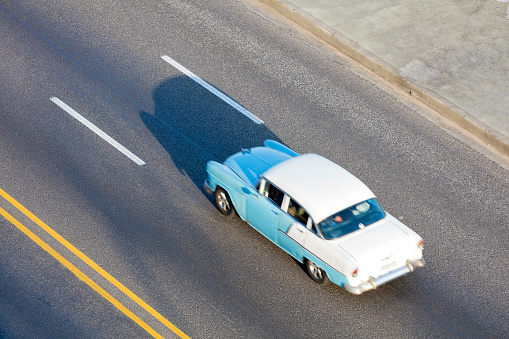 Blue vintage American car speeding along the Malecon in Havana, Cuba, motion blur, 50 megapixel image.