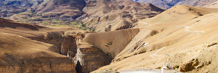 Panorama of the Himalayas, the Kibber village and leading to it among steep gorges winding mountain road. Spiti Valley, northern India