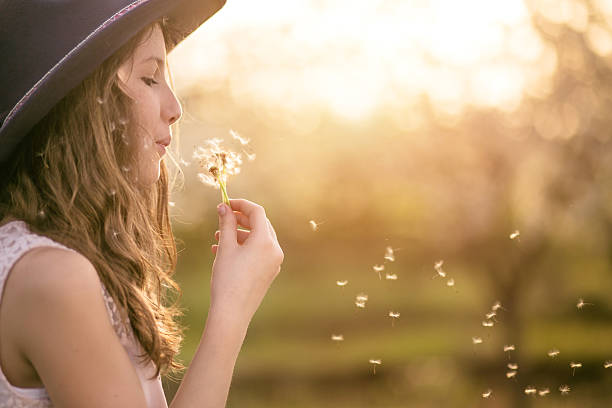 Young girl outside blowing dandelion-copy space
