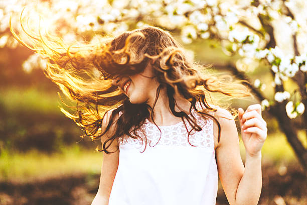 Shot of a beautiful carefree young woman flinging her hair while dancing outdoors in cherry blossom orchard