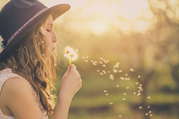 istock Young hippie girl blowing dandelion outside 538468100