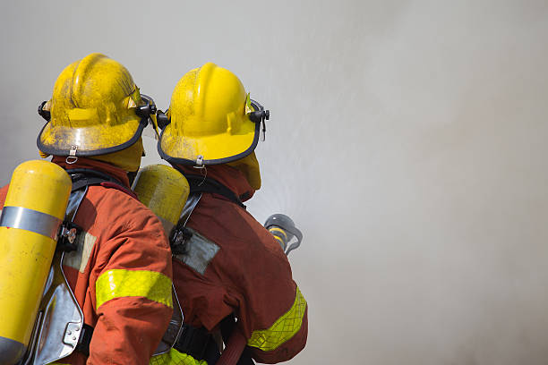 istock 2 firemen spraying water in fire and smoke 538468594