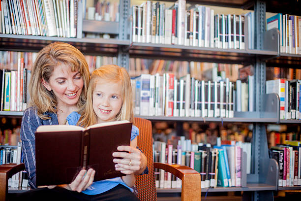 istock Mother and daughter reading together in library 538472342