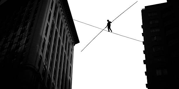 Man balancing on rope high in the sky stock photo