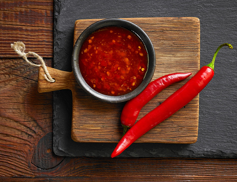 bowl of red hot chili sauce on black stone background