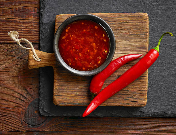 red hot chili sauce bowl of red hot chili sauce on black stone background condiment stock pictures, royalty-free photos & images