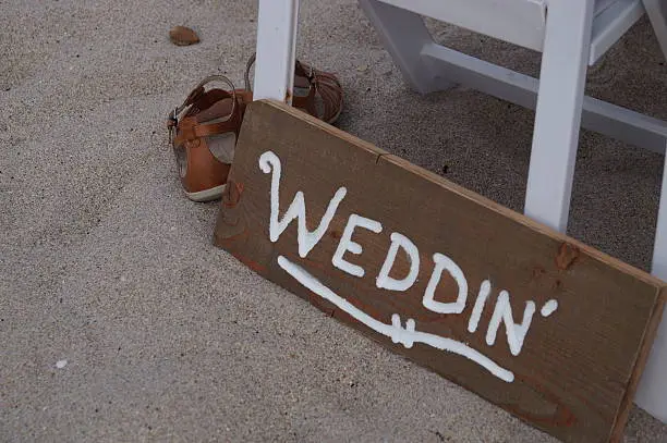 Wedding sign in sand near sandals