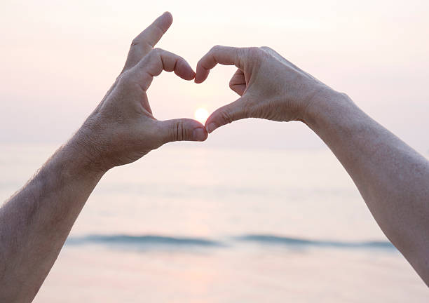 istock Couple put hands together to form heart, sunrise 538476043
