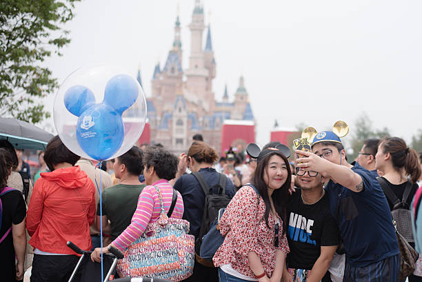 Shanghai, China - June 7, 2016: A group of young chinese people taking a selfie with the Enchanted Castle on the back,  during trial operations before the grand opening of Shanghai Disneyland Park, located in Chuansha New Town of Pudong New Area, which is officially confirmed to open on June 16th, 2016. Is the sixth in the world and the second in China (after Hong Kong Disneyland).