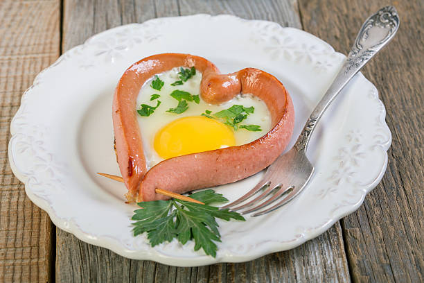 coração em forma de linguiça e ovos mexidos. - eggs breakfast heart shape fried egg - fotografias e filmes do acervo