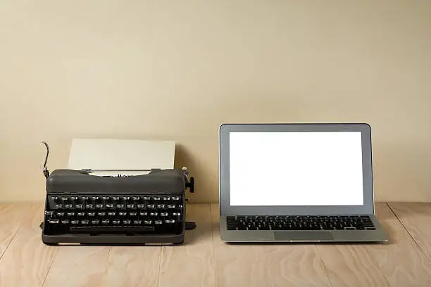 Image of vintage typewriter and modern laptop on wooden table