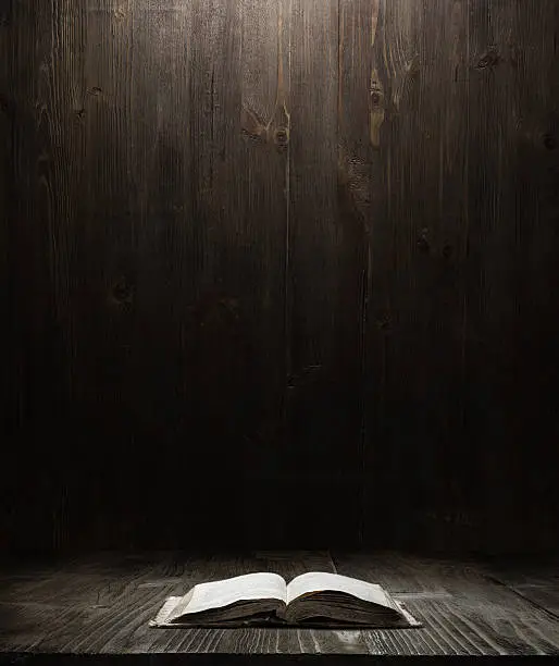dark wooden background texture. Wood shelf, grunge industrial interior with a bookImage of the Holy Bible on wooden background in a dark space