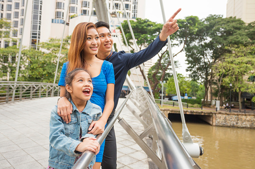 A happy young Asian family sightseeing on a bridge in Singapore