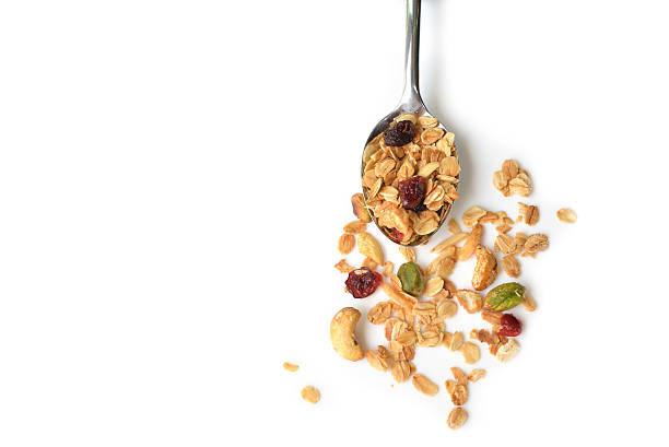 Homemade granola in a spoon Homemade granola with honey, oatmeal, cashew nut, almond, pistachio, raisin and cranberry on white background granola stock pictures, royalty-free photos & images