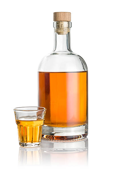 istock Bottle and beveled shot glass filled with amber liquid 538482297