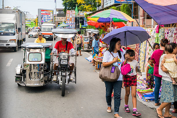 Street in Batangas, Philippines Batangas, Philippines - May 1, 2016: Motorists seen on a street in Batangas, Philippines. Pedestrians and small shops by the side of the road. philippines tricycle stock pictures, royalty-free photos & images