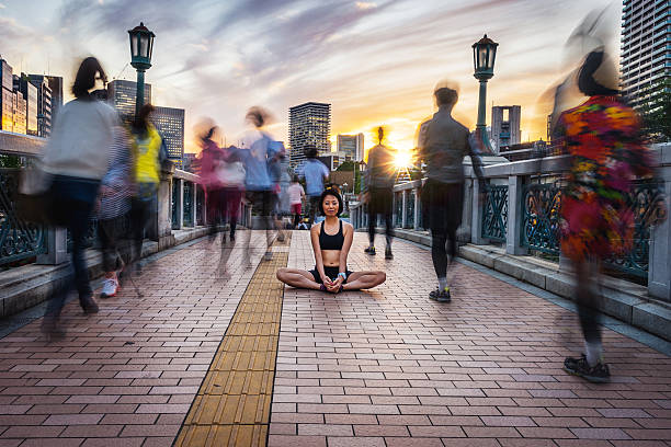 mujer meditando en la multitud al anochecer - blurred motion motion group of people crowded fotografías e imágenes de stock