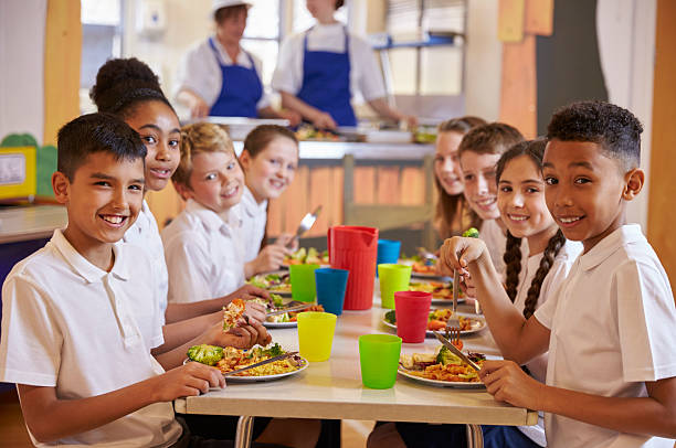 ragazzi un un tavolo in un scuola caffetteria look - child food school children eating foto e immagini stock