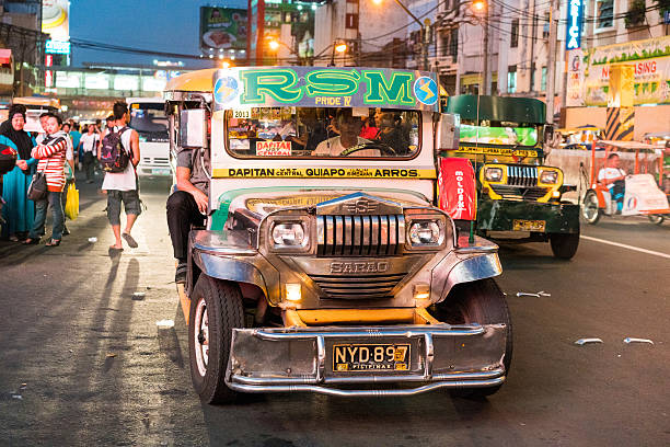 Manila, Philippines - May 17, 2016: A Dapitan bound jeepney full of passengers making its way through the streets of Quiapo in Manila, Philippines at night. People can be seen walking around.