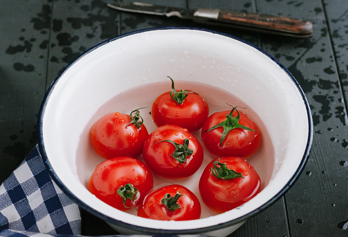 Group of tomatoes in white metal bowl