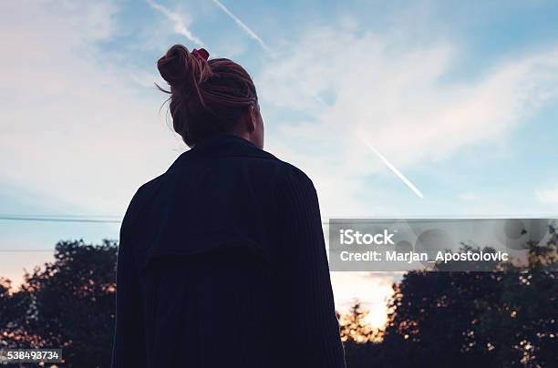 La Silueta De Una Mujer Joven Observando Un La Puesta De Sol Foto de stock y más banco de imágenes de Vista posterior