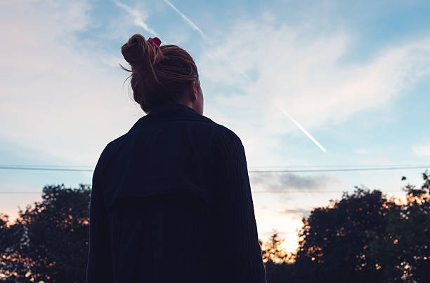 la silhouette de la jeune femme regardant le coucher du soleil - vue en contre plongée verticale photos et images de collection