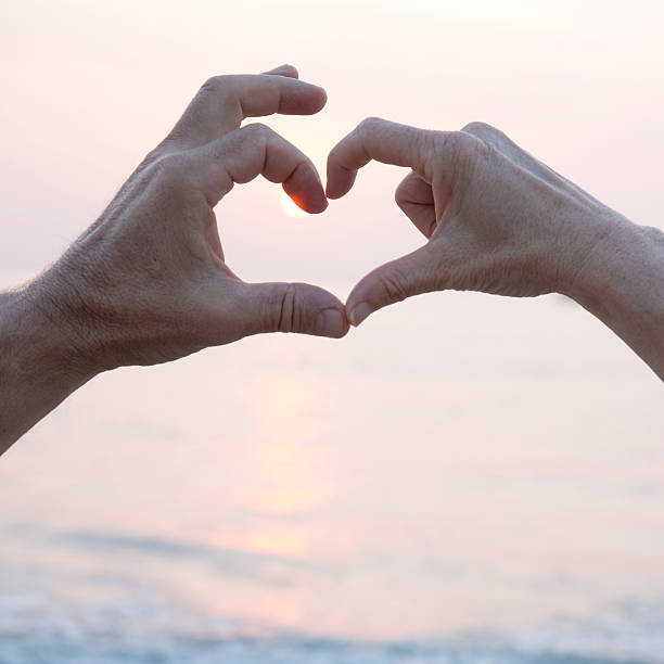 istock Couple put hands together to form heart, sunrise 538503965