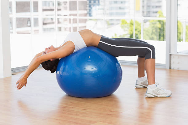 istock Fit woman stretching on exercise ball at gym 538506347