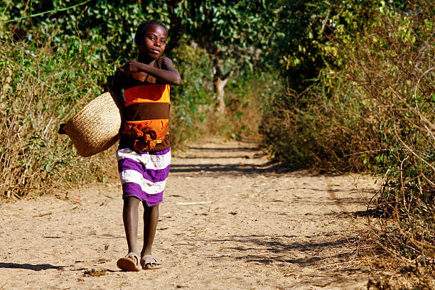 istock Poor african girl walking the path with basket in hand 538526967