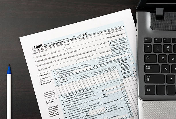 istock 1040 Individual tax return form close-up with pen, laptop computer 538528621