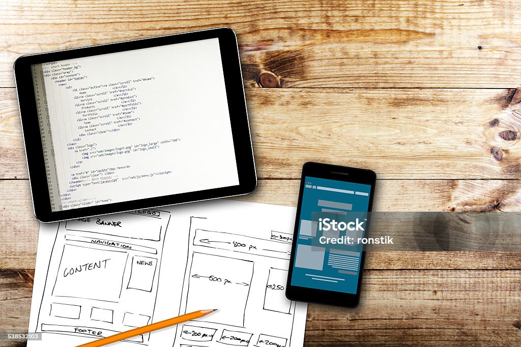 website wireframe sketch and programming code on digital tablet website wireframe sketch and digital tablet with programming code on wooden table. programming code is my own property Web Page Stock Photo