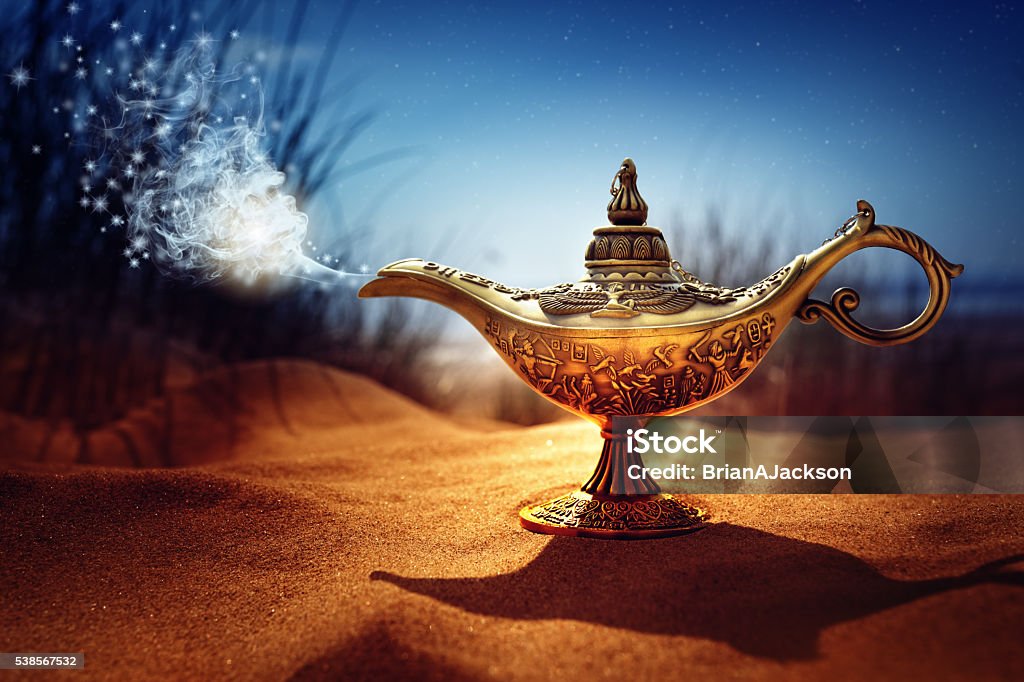 Magic Aladdins Genie lamp Magic lamp in the desert from the story of Aladdin with Genie appearing in blue smoke concept for wishing, luck and magic Wishing Stock Photo
