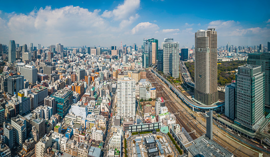 Big blue spring skies and white fluffy clouds over the soaring skyscrapers and towering high rises of central Tokyo, Japan's massive capital city. ProPhoto RGB profile for maximum color fidelity and gamut.