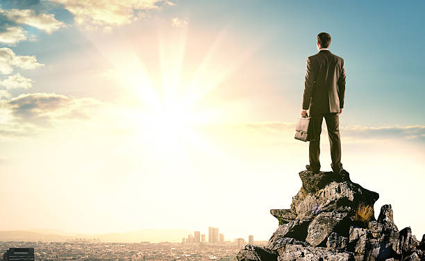 istock Businessman standing on edge of rock mountain 538575422