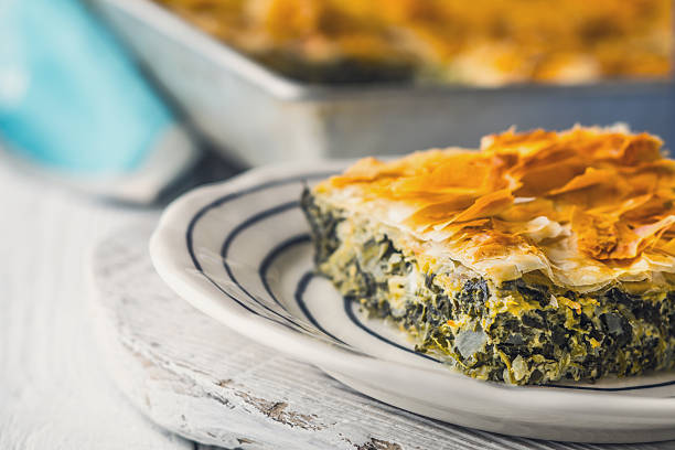 Greek pie spanakopita in the ceramic  plate on the white wooden table horizontal