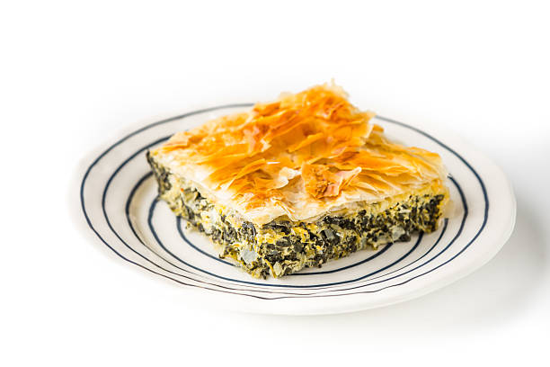 кусочек греческого пирога спанакопита на белом фоне - pie spinach spanakopita filo pastry стоковые фото и изображения