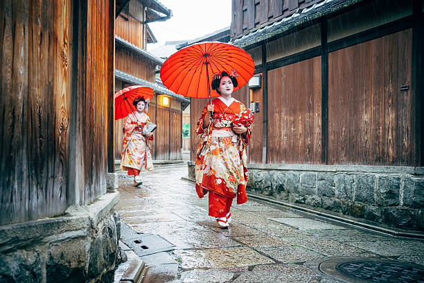 haltestelle maiko frauen wandern in kyoto - parasol umbrella asian ethnicity asian culture stock-fotos und bilder