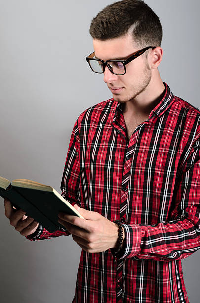 istock young student wearing glasses and reading book on grey background 538593558