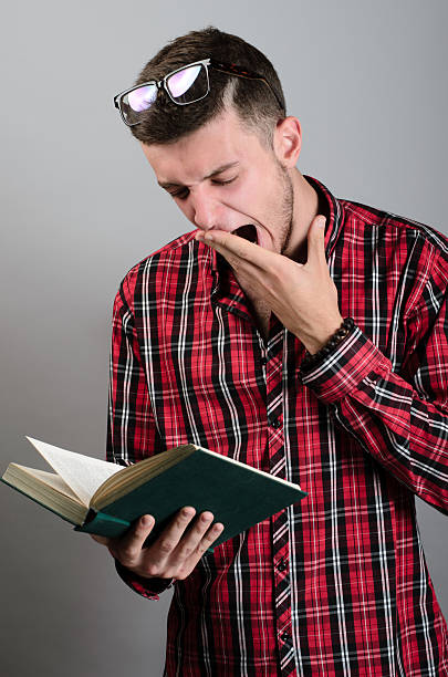 istock young student wearing glasses, reading book and yawning 538594000