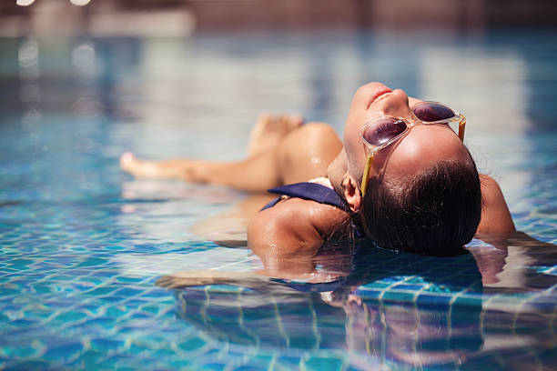 Portrait of sexy cheerful woman relaxing at the luxury poolside. stock photo