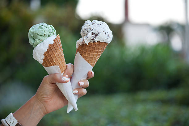 Two colorful tasty ice cream cones in hand. stock photo