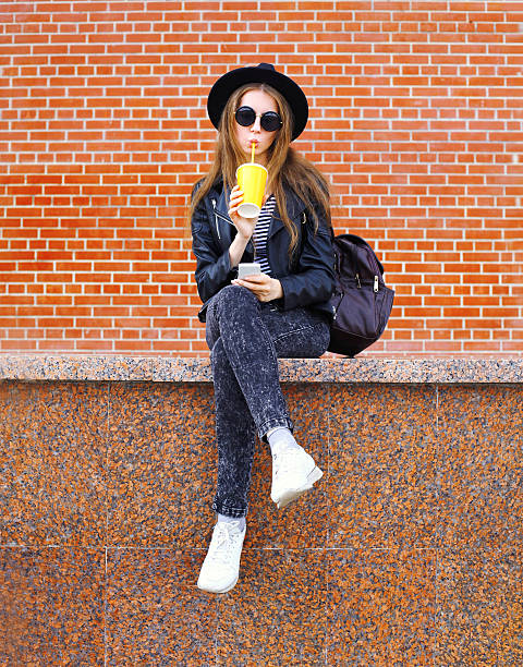 istock Fashion pretty woman drinks juice from cup using smartphone 538600252