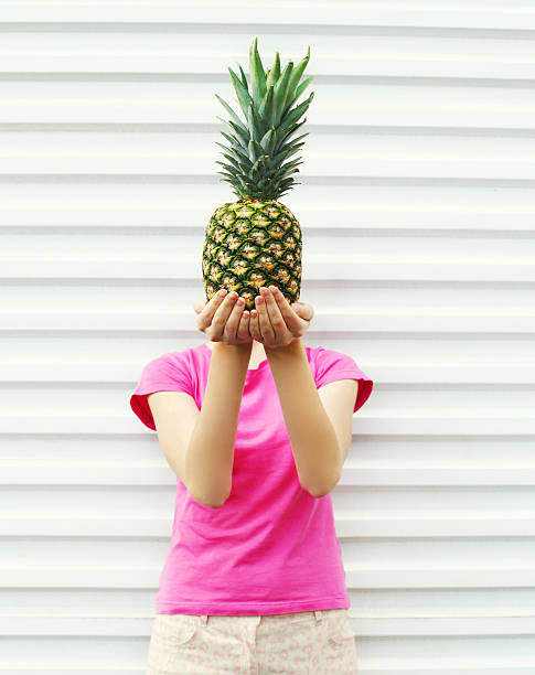 istock Woman and pineapple on her head standing over white background 538601436