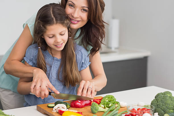 istock Smiling woman with daughter chopping vegetables in kitchen 538621707