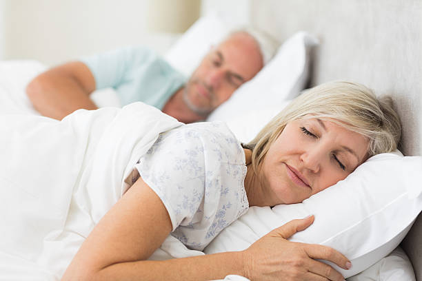 mature couple sleeping with eyes closed in the bed - ogen dicht closeup vrouw 50 jaar stockfoto's en -beelden