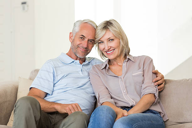 istock Smiling mature couple sitting on sofa with arm around 538623231