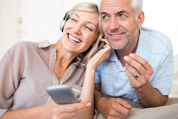 mature couple with headphones and cellphone - ogen dicht closeup vrouw 50 jaar stockfoto's en -beelden